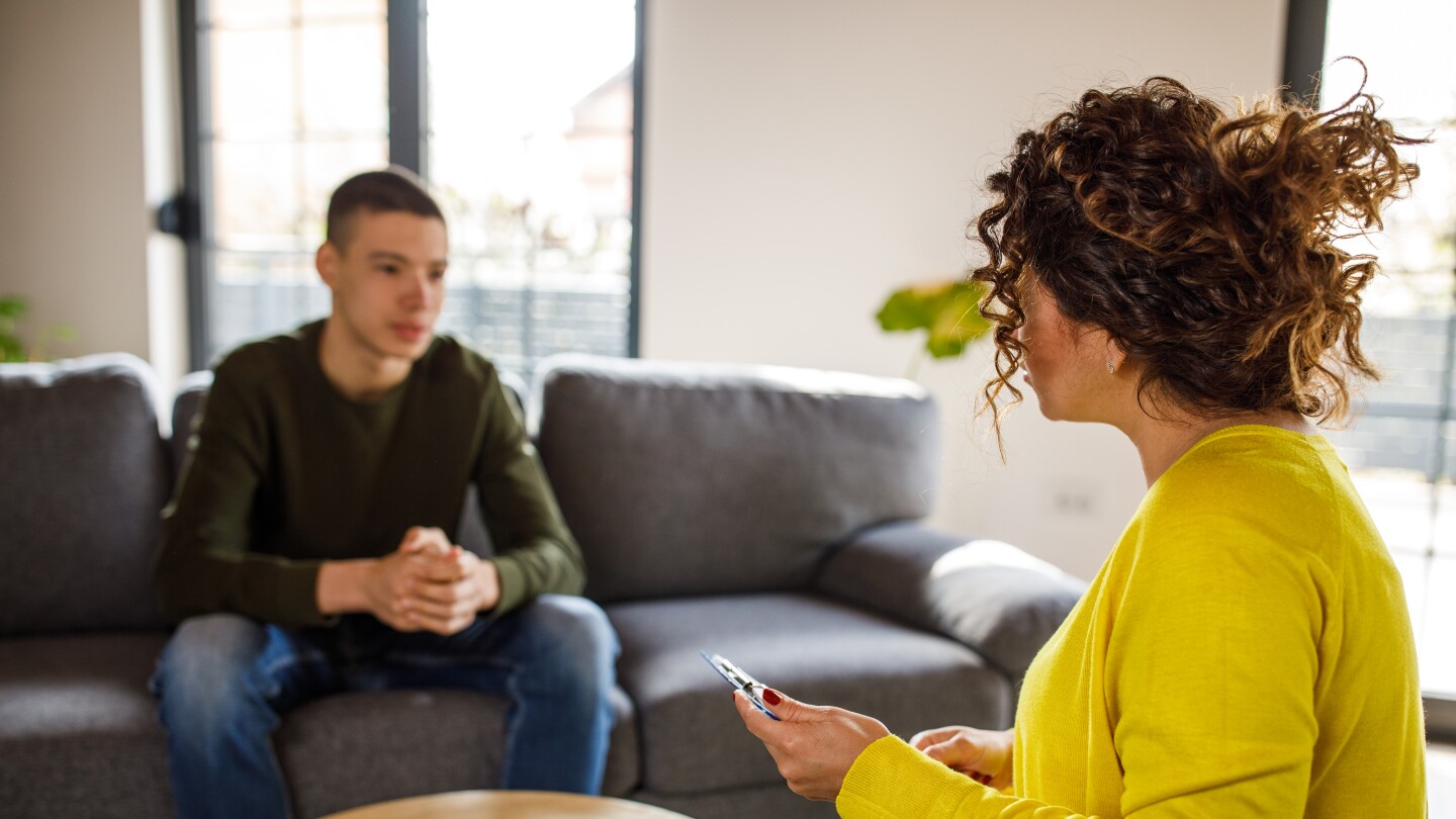 Caring female therapist talking with insecure teenage boy