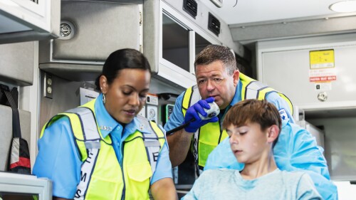 Paramedics inside ambulance with teenage boy on stretcher