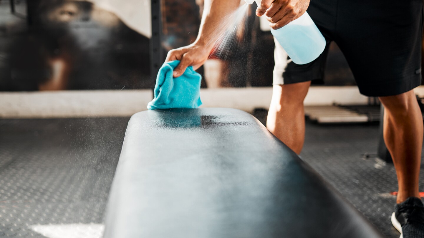 Shot of a business owner sanitizing the work benches in their gym