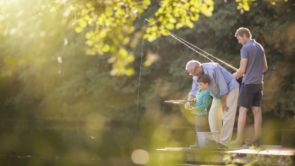 Boy, father and grandfather fishing in lake