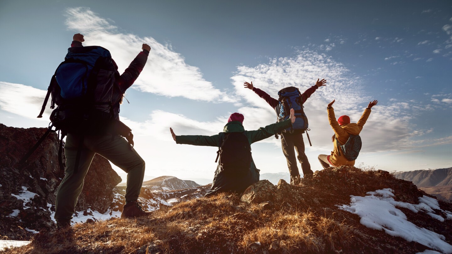 Hikers in winner poses stands at mountain top
