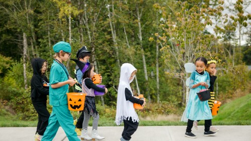 Children Trick Or Treat For Halloween In Residential Neighborhood