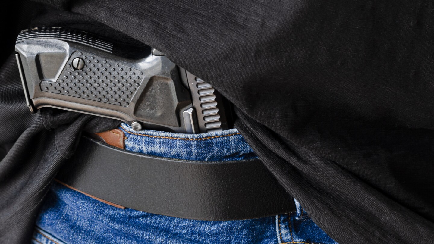 Gun. Hided handgun under the denim belt.