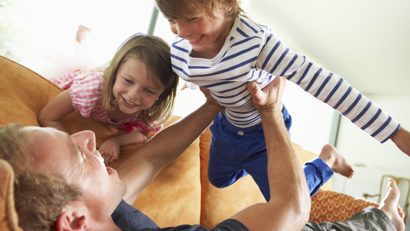 Father And Children Lying On Sofa At Home
