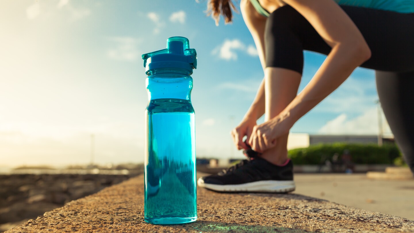 Female runner tying her shoes next to bottle of water