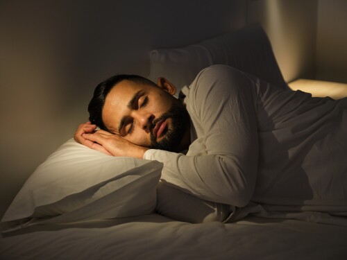 Young man sleeping peacefully in his bed at night