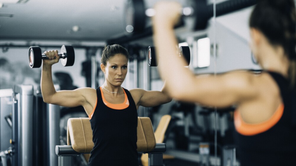 Young woman exercising in front of the mirror